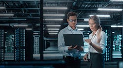 man-and-woman-reviewing-information-on-laptop-in-a-data-center